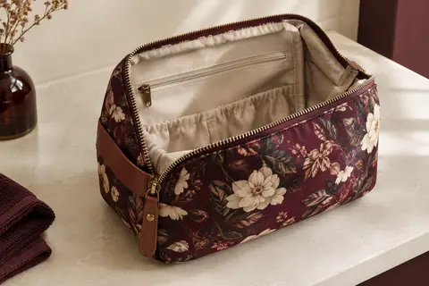 Trousse de toilette Cabaia à motif floral, avec ouverture grand angle, posée dans un intérieur crème