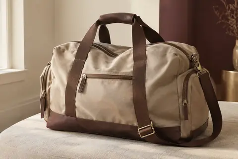 Sac de voyage fourre-tout beige et marron en polyester, avec compartiment inférieur et poches de rangement.